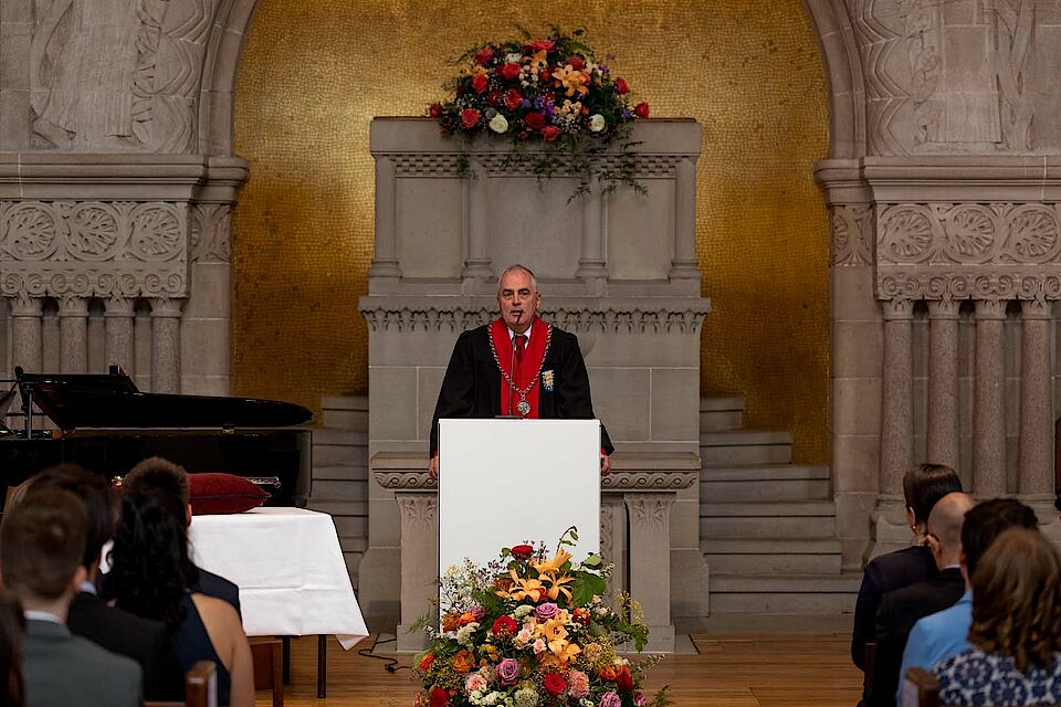 Bild der Ansprache von Prof. Dr. Wolfgang Wohlers, Dekan der Juristischen Fakultät, an einem Rednerpult stehend vor Publikum.