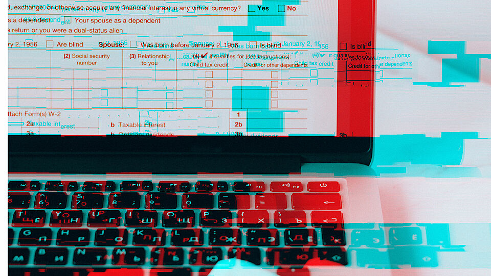 Image detail of a laptop screen and associated keyboard with blue-red patterns in the background.