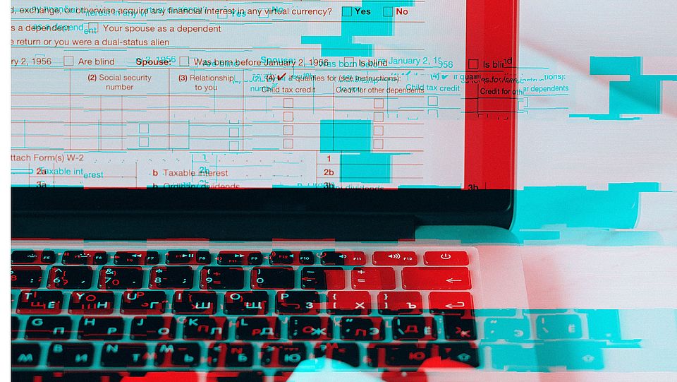 Image detail of a laptop screen and associated keyboard with blue-red patterns in the background.