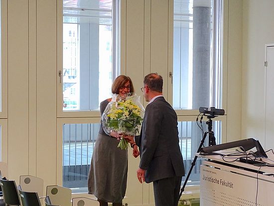 Szene der Veranstaltung Rousseau Lectures 2023 im Auditorium der Juristischen Fakultät mit Blumenübergabe an eine Sprecherin.