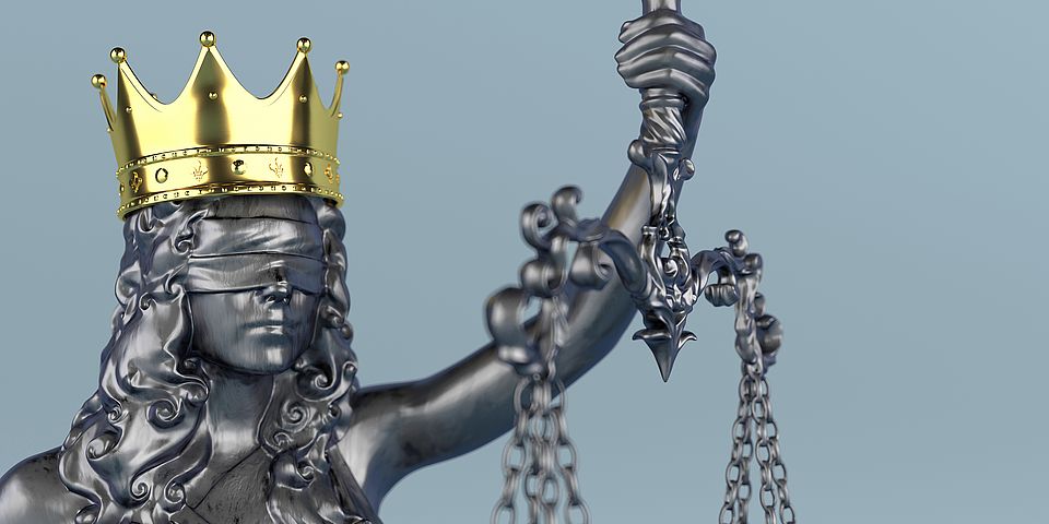 Bild der Justitia, Göttin der Gerechtigkeit, als eiserne Statue mit goldener Krone auf dem Haupt.