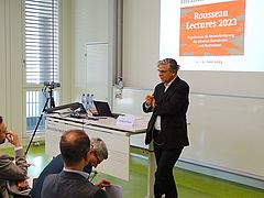 Szene der Veranstaltung Rousseau Lectures 2023 im Auditorium der Juristischen Fakultät mit Sprecher im Vordergrund rechts und zuhörendem Publikum links.