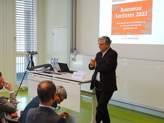 Szene der Veranstaltung Rousseau Lectures 2023 im Auditorium der Juristischen Fakultät mit Sprecher im Vordergrund rechts und zuhörendem Publikum links.