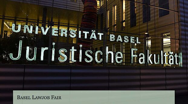 Rückansicht der Juristischen Fakultät bei Nacht, von der Nauenstrasse her mit dem beleuchteten Schriftzug der Fakultät im Fokus.